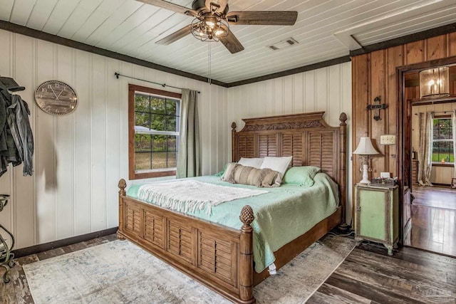 bedroom featuring multiple windows, ceiling fan, dark wood-type flooring, and wood walls