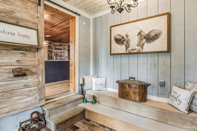 room details featuring a barn door, wooden walls, and wooden ceiling