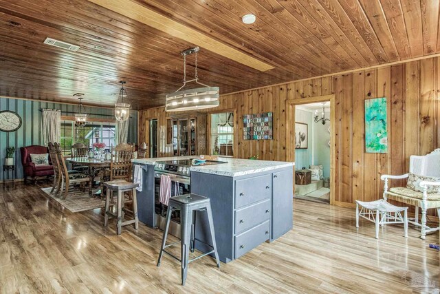 kitchen with pendant lighting, wood walls, wooden ceiling, light hardwood / wood-style flooring, and light stone counters