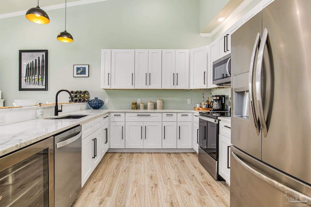 kitchen with beverage cooler, appliances with stainless steel finishes, decorative light fixtures, crown molding, and a sink