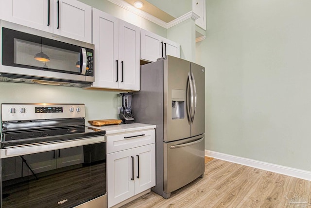 kitchen with light wood finished floors, baseboards, appliances with stainless steel finishes, and light countertops