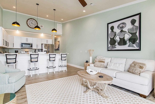 living room with crown molding, visible vents, light wood-style flooring, a high ceiling, and baseboards