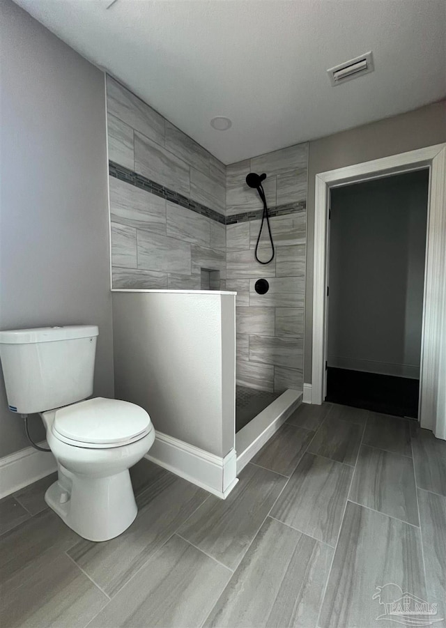 bathroom with tiled shower and toilet