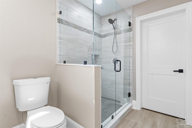 bathroom featuring toilet and a shower with shower door