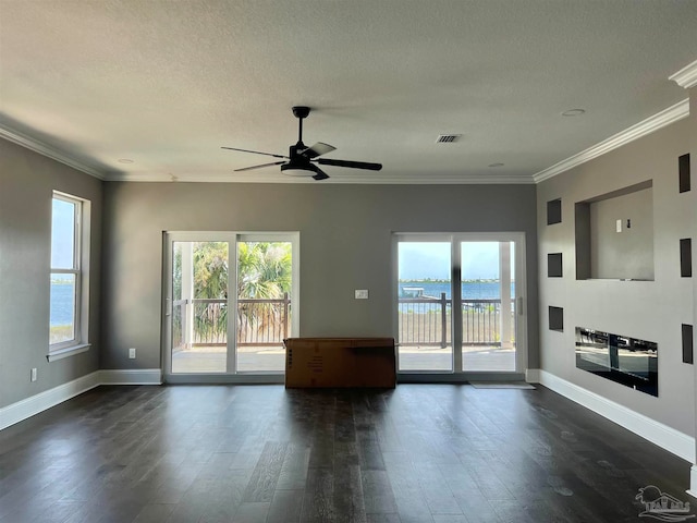 spare room featuring dark hardwood / wood-style flooring, a water view, ornamental molding, and a textured ceiling