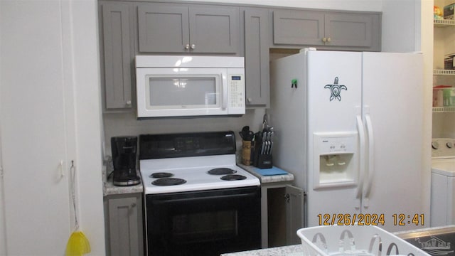 kitchen with gray cabinets, washer / clothes dryer, and white appliances