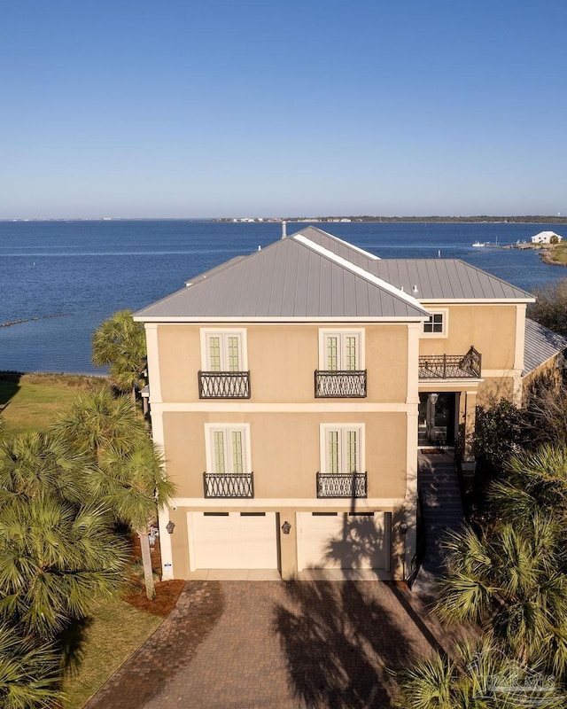 106 Matamoros Dr, Pensacola Beach, FL 32561 - exterior space with stucco siding, a balcony, decorative driveway, a water view, and a garage