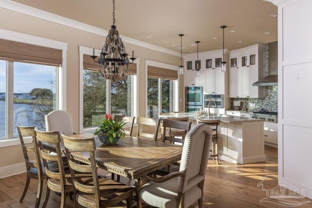 106 Matamoros Dr, Pensacola Beach, FL 32561 - dining room with light wood-type flooring, crown molding, and a healthy amount of sunlight