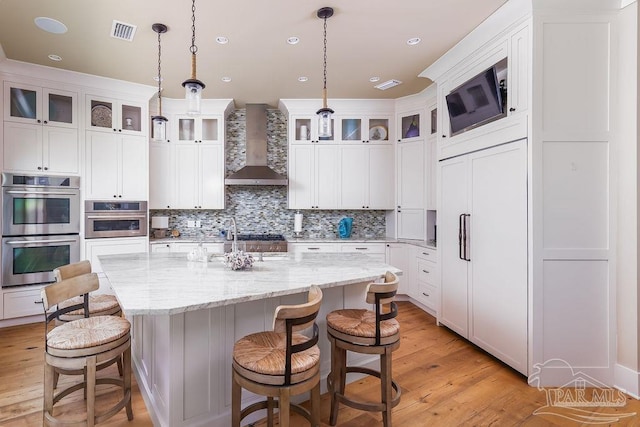 106 Matamoros Dr, Pensacola Beach, FL 32561 - kitchen featuring light wood-style floors, visible vents, wall chimney exhaust hood, and double oven