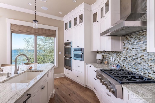 106 Matamoros Dr, Pensacola Beach, FL 32561 - kitchen featuring a sink, pendant lighting, wall chimney exhaust hood, appliances with stainless steel finishes, and dark wood-type flooring