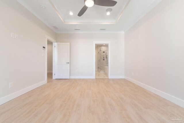 unfurnished bedroom with ensuite bath, ceiling fan, a raised ceiling, and light hardwood / wood-style floors