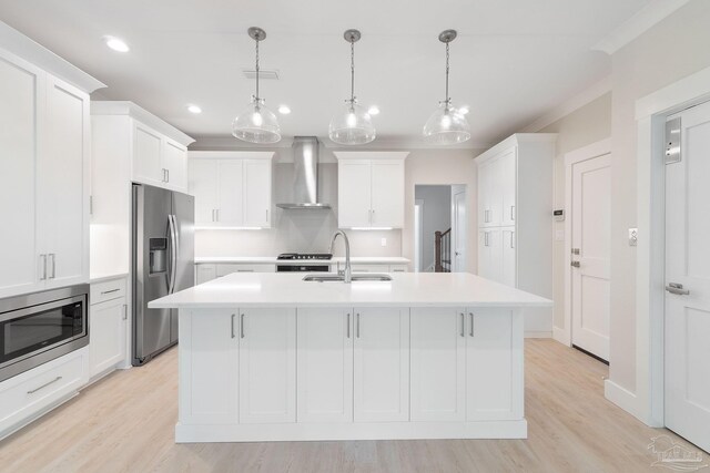 kitchen with sink, appliances with stainless steel finishes, light hardwood / wood-style flooring, and wall chimney range hood