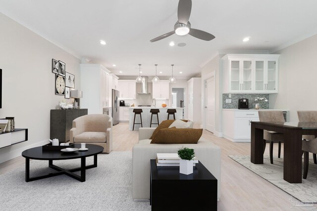 living room featuring ceiling fan, sink, light hardwood / wood-style flooring, and ornamental molding