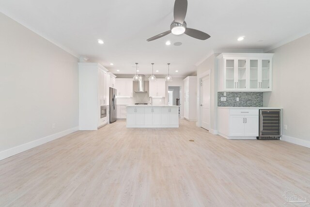 unfurnished living room featuring crown molding, light wood-type flooring, ceiling fan, and wine cooler