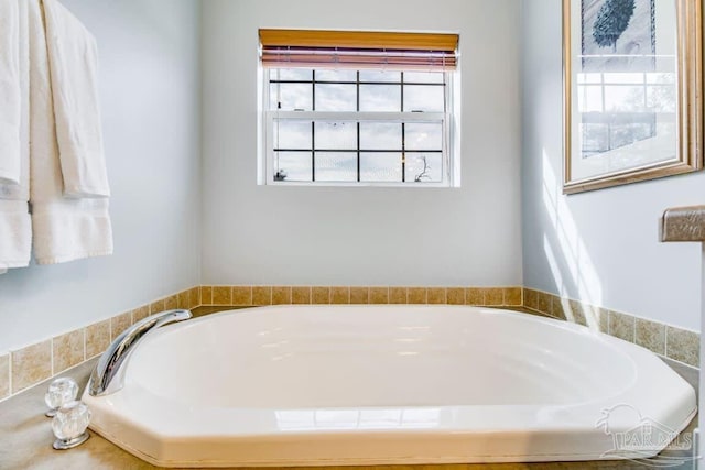 bathroom featuring a relaxing tiled tub and a healthy amount of sunlight