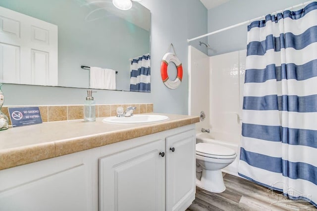 full bathroom featuring hardwood / wood-style flooring, shower / bathtub combination with curtain, vanity, and toilet