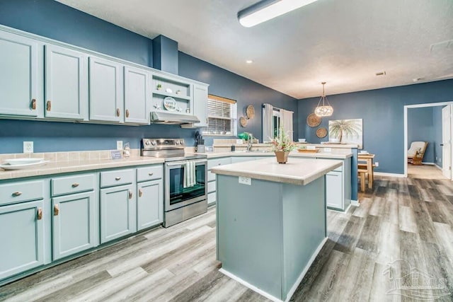 kitchen featuring a kitchen island, decorative light fixtures, sink, light hardwood / wood-style floors, and electric stove