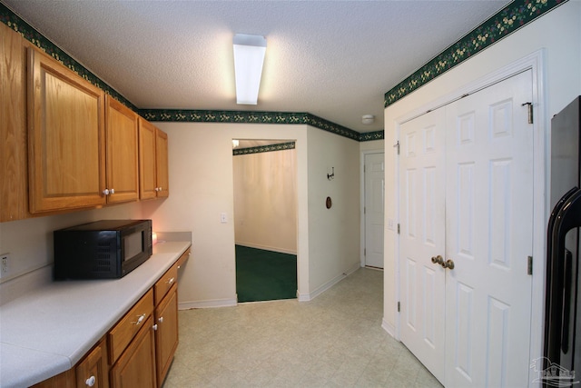 1701 Lighthouse Pointe Dr, Gulf Breeze, FL 32563 - kitchen with black microwave, freestanding refrigerator, brown cabinetry, light countertops, and light flooring