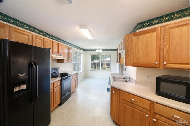 1701 Lighthouse Pointe Dr, Gulf Breeze, FL 32563 - kitchen featuring black appliances, a sink, under cabinet range hood, light countertops, and light floors
