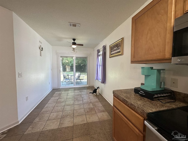 interior space featuring ceiling fan, baseboards, a textured ceiling, and dark tile patterned flooring