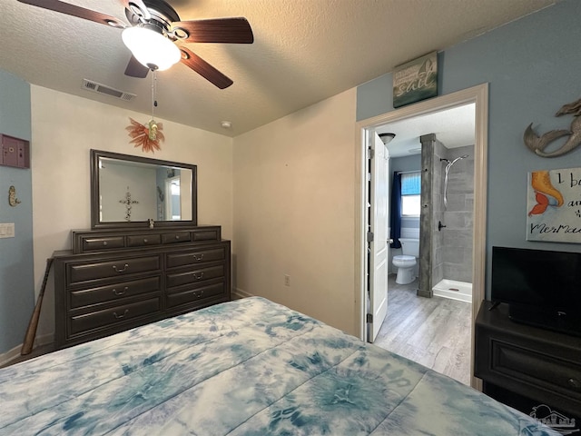 bedroom featuring wood finished floors, a textured ceiling, connected bathroom, a ceiling fan, and baseboards