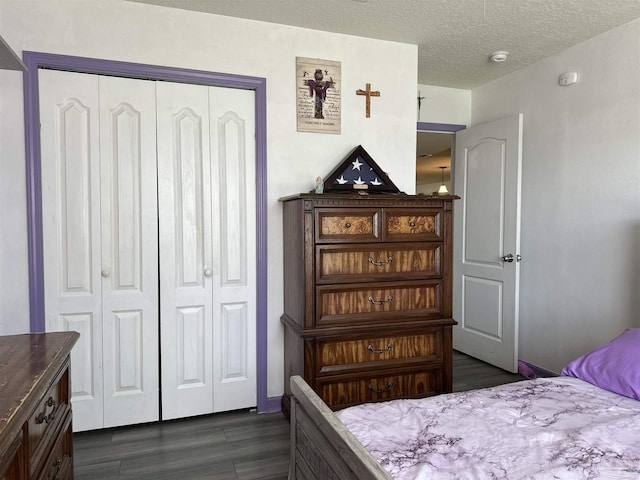 bedroom with a closet, dark wood finished floors, and a textured ceiling
