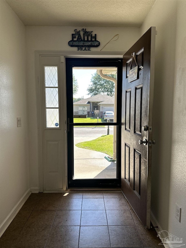 foyer with tile patterned flooring, baseboards, and a textured ceiling