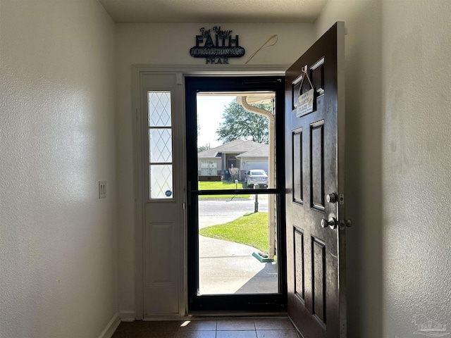 doorway to outside with tile patterned flooring, baseboards, and a textured wall
