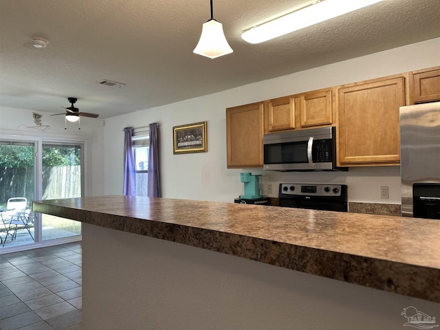 kitchen featuring appliances with stainless steel finishes, a ceiling fan, pendant lighting, dark tile patterned flooring, and dark countertops