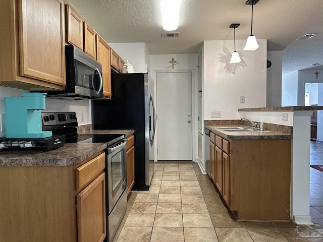 kitchen featuring stainless steel appliances, a sink, dark countertops, a peninsula, and a textured ceiling