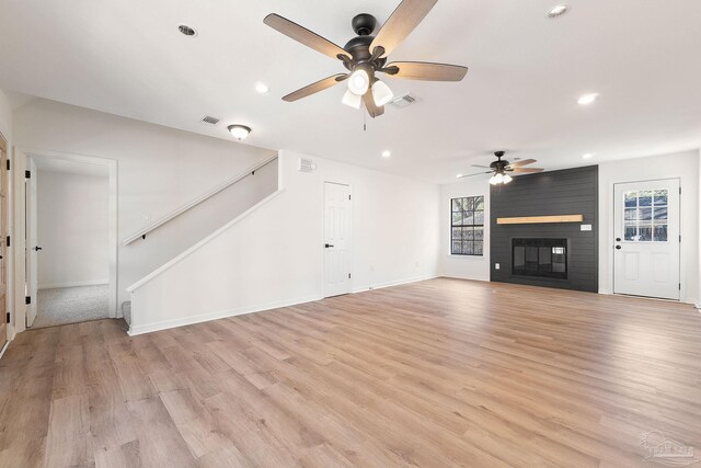 unfurnished living room with visible vents, plenty of natural light, and stairs