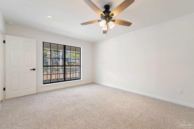 carpeted empty room featuring ceiling fan and baseboards