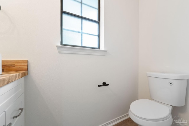 bathroom featuring baseboards, toilet, and vanity