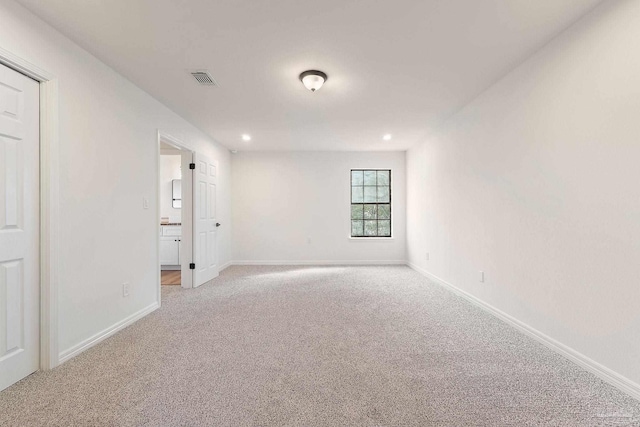 spare room featuring recessed lighting, light colored carpet, and baseboards