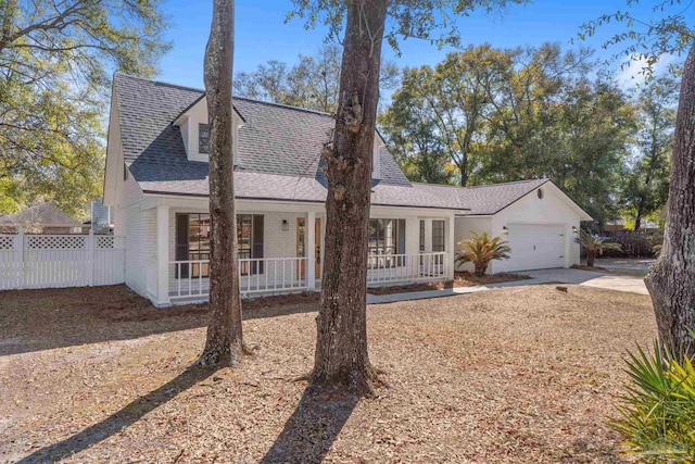 view of front of house featuring a porch, a shingled roof, an attached garage, and fence