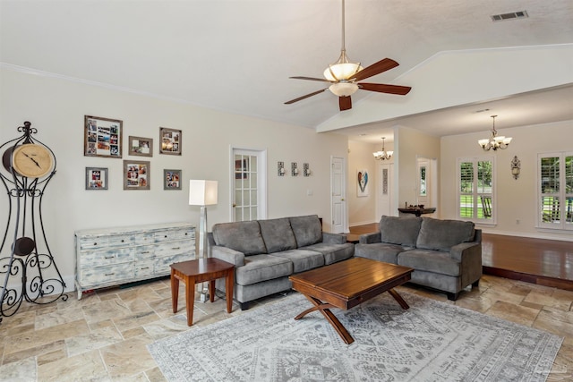 living area with stone tile floors, lofted ceiling, visible vents, baseboards, and ceiling fan with notable chandelier