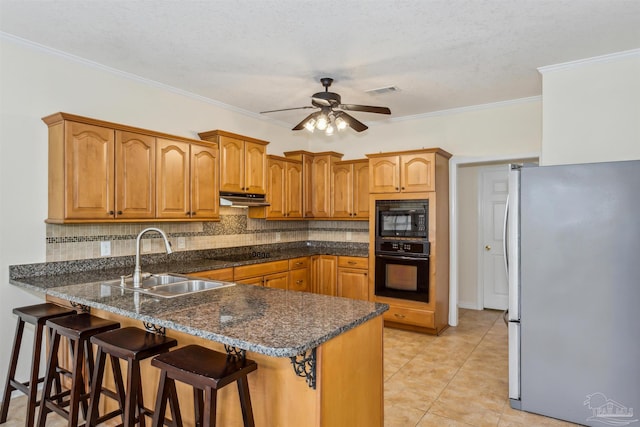 kitchen with a peninsula, under cabinet range hood, black appliances, a kitchen bar, and a sink