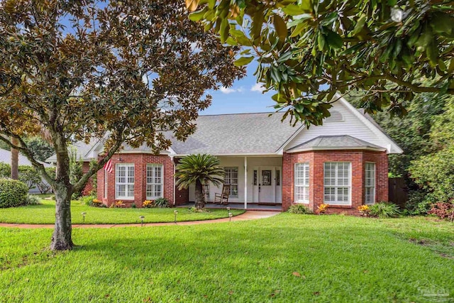 view of front of home with brick siding, a front yard, and a shingled roof