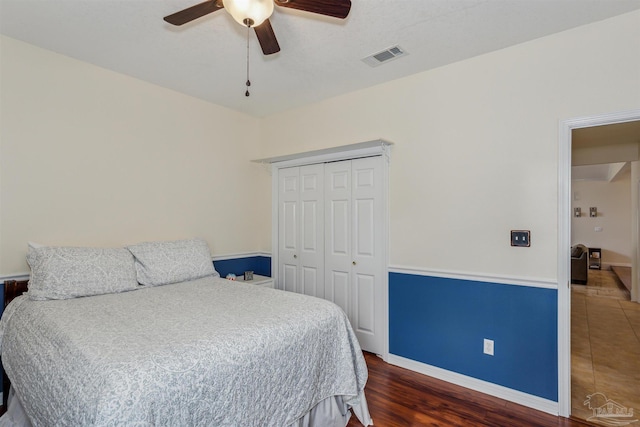 bedroom with wood finished floors, a ceiling fan, visible vents, baseboards, and a closet