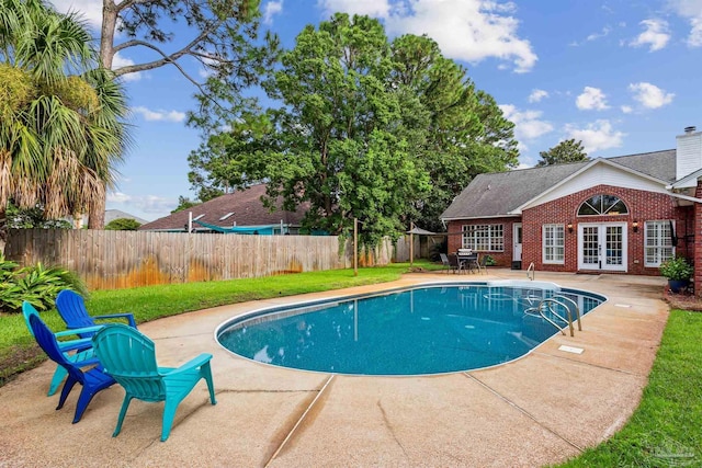 view of pool featuring a fenced backyard, a yard, french doors, a fenced in pool, and a patio area