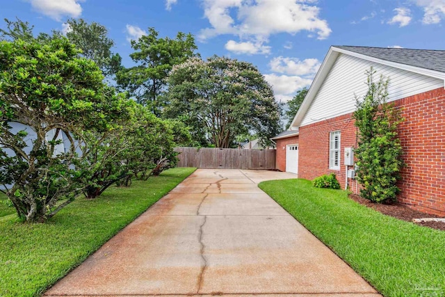 view of yard with a garage, driveway, and fence