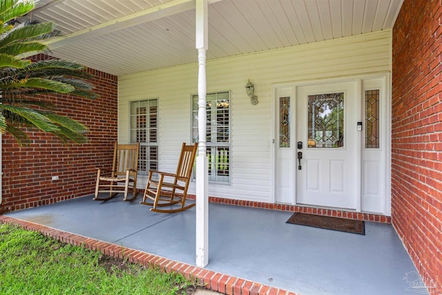 view of exterior entry with covered porch and brick siding