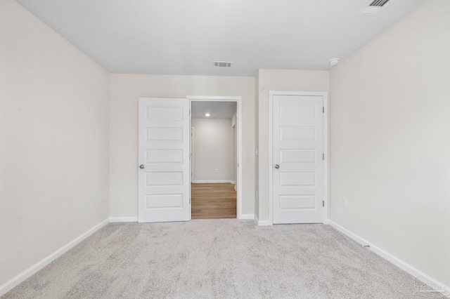 unfurnished bedroom with a closet and light colored carpet