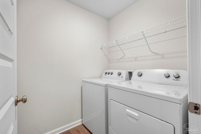 washroom with wood-type flooring and washing machine and dryer