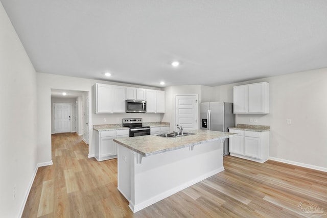 kitchen featuring white cabinets, sink, a center island with sink, stainless steel appliances, and light hardwood / wood-style floors