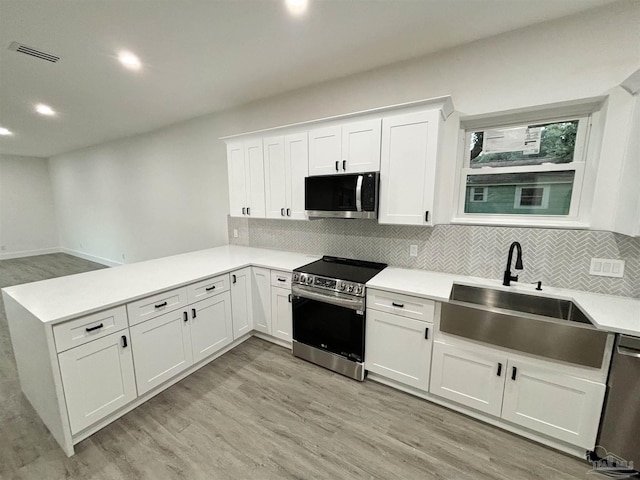 kitchen with white cabinets, stainless steel appliances, light hardwood / wood-style flooring, and sink