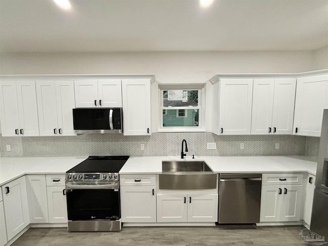 kitchen with sink, white cabinetry, stainless steel appliances, and light wood-type flooring