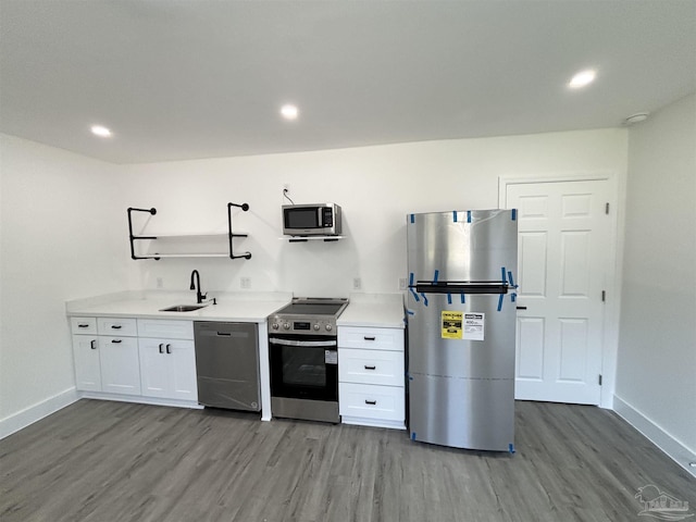 kitchen with hardwood / wood-style floors, stainless steel appliances, white cabinetry, and sink