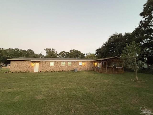 back house at dusk featuring a yard