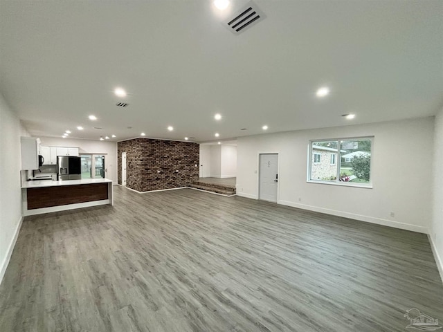 unfurnished living room featuring light hardwood / wood-style floors and brick wall